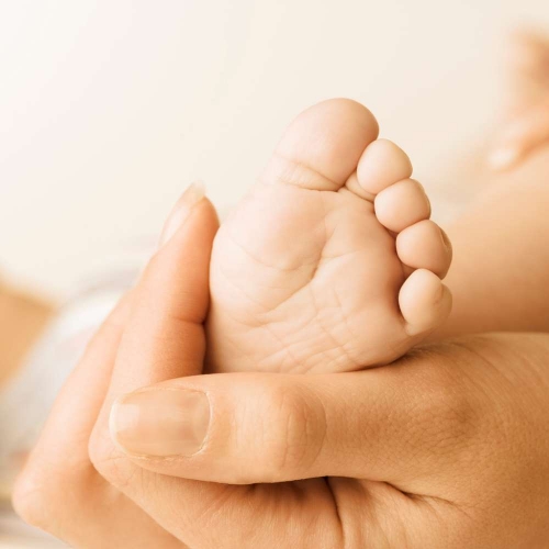 Une mère tenant le pieds de son enfant